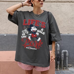Pu&ograve; includere: T-shirt oversize grigio scuro con Topolino e la scritta "Life's a Walk in the Park" e "Walt Disney World" in rosso e bianco. La maglietta ha maniche corte.