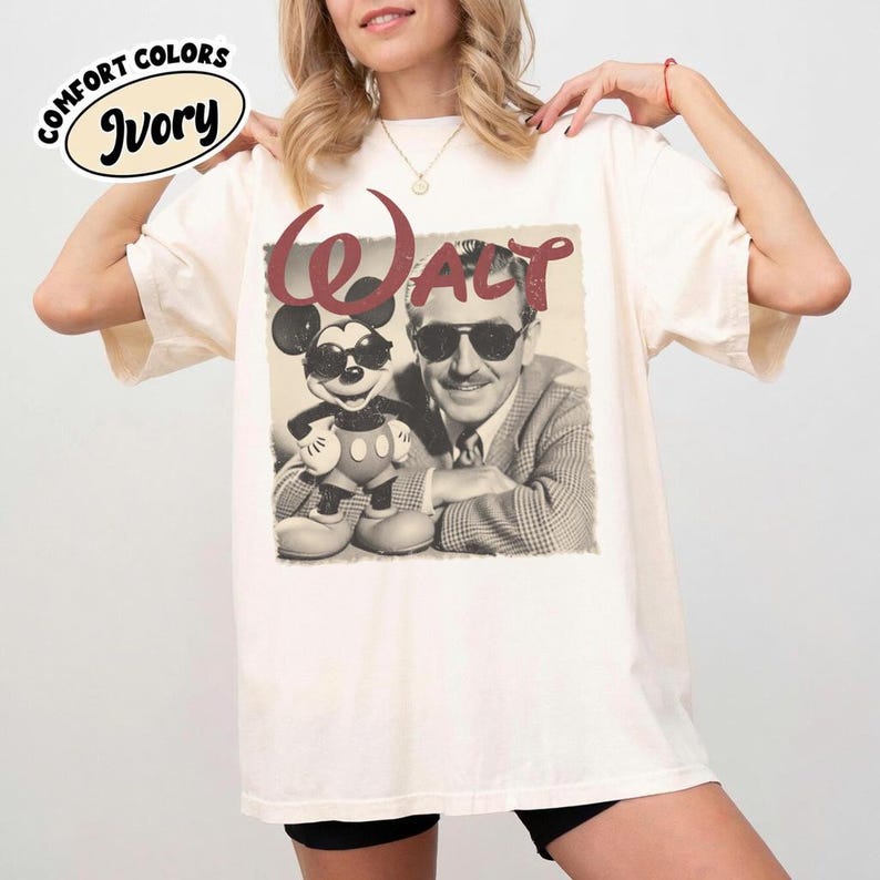 Pu&ograve; includere: T-shirt color avorio con un'immagine color seppia di Topolino con occhiali da sole accanto a Walt Disney. La parola "WALT" &egrave; stampata sopra l'immagine in uno script bordeaux. La maglietta ha le parole "COMFORT COLORS" e "Ivory" stampate in alto a sinistra.
