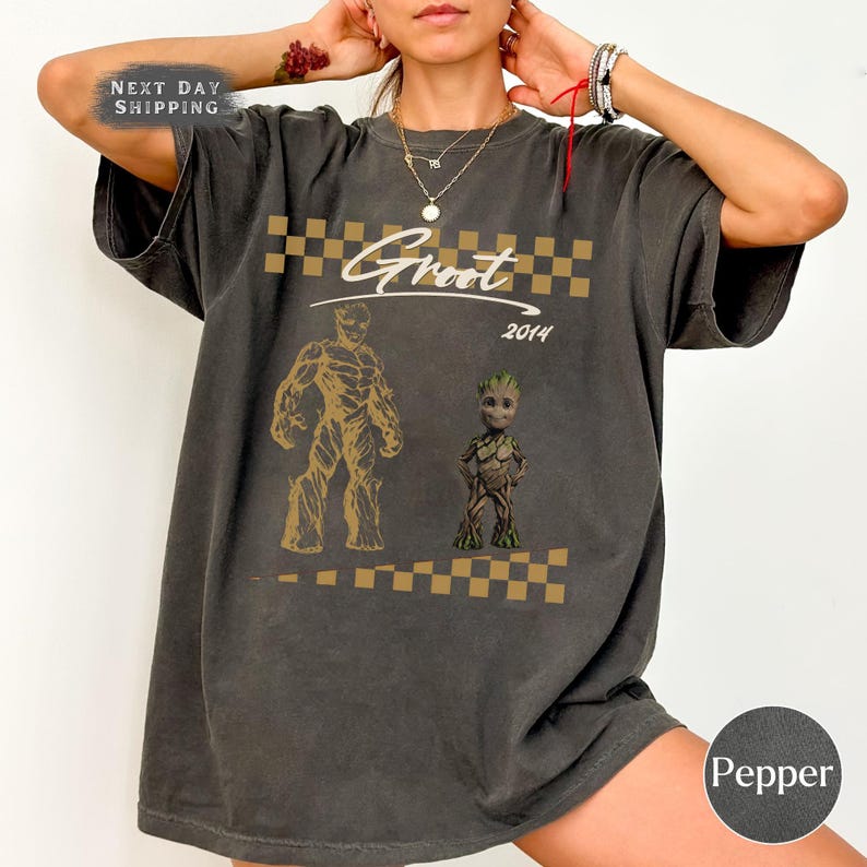 May include: Dark gray t-shirt featuring two Groot illustrations in gold, with the word "Groot" above and "2014" below. The shirt has a checkered pattern and the text "Next Day Shipping".
