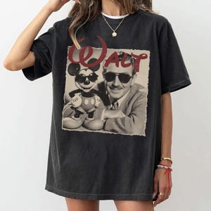 Pu&ograve; includere: T-shirt nera con grafica vintage di Walt Disney e Mickey Mouse con occhiali da sole. La parola "WALT" &egrave; stampata in rosso sopra l'immagine. La maglietta ha una vestibilit&agrave; ampia e maniche corte.