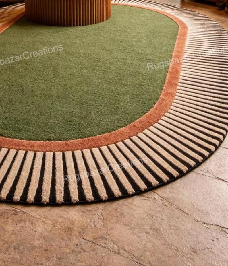 May include: A round area rug with a green center, a rust-colored border, and a striped outer edge. The stripes alternate between black and beige. The rug is placed on a stone floor.