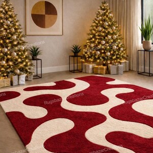 Puede incluir: Una alfombra roja y crema con un patr&oacute;n ondulado. La alfombra est&aacute; en una habitaci&oacute;n decorada para Navidad, con dos &aacute;rboles de Navidad iluminados, regalos envueltos y una pintura moderna en la pared.