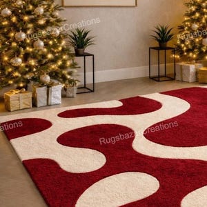 Puede incluir: Una alfombra roja y crema con un dise&ntilde;o abstracto. La alfombra presenta un patr&oacute;n ondulado en rojo sobre un fondo crema. La habitaci&oacute;n est&aacute; decorada para las fiestas con &aacute;rboles de Navidad y regalos.