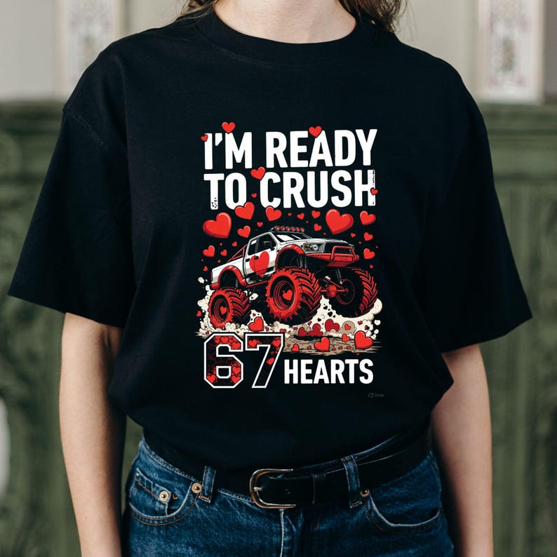May include: Black t-shirt with a graphic featuring a monster truck design. The text reads "I'M READY TO CRUSH" above the truck and "67 HEARTS" below. Red hearts are scattered around the truck and text.