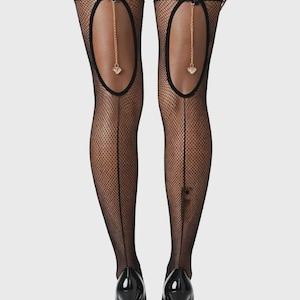 May include: Black fishnet stockings featuring a thigh-high design with a solid black top band. Each stocking includes an oval cutout at the upper thigh adorned with a small black bow and a dangling gold-tone chain ending in a heart-shaped charm.