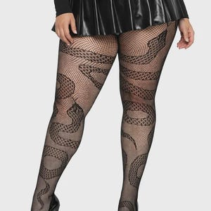 May include: Black fishnet tights with a snake design. The tights have a detailed pattern of snakes. The model is wearing black platform heels and a black pleated skirt. The overall look is edgy and stylish.