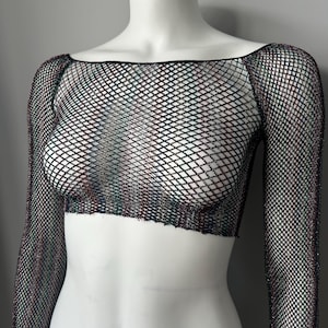 May include: A long-sleeve crop top made of black fishnet material with a subtle iridescent shimmer. The garment features a wide, straight neckline and a cropped hemline that sits above the waist, showcasing a diamond-shaped mesh pattern throughout.