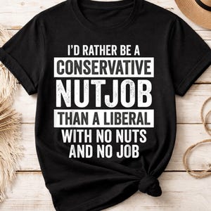 May include: Black t-shirt with white text that reads: "I'D RATHER BE A CONSERVATIVE NUTJOB THAN A LIBERAL WITH NO NUTS AND NO JOB." The shirt has short sleeves and a crew neck.
