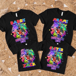 Pode incluir: Quatro camisetas pretas com designs gr&aacute;ficos coloridos. As camisas s&atilde;o rotuladas como "Daddy", "Mommy", "Sister" e "Jack", com um gr&aacute;fico de "Birthday Boy". As camisas est&atilde;o em uma superf&iacute;cie tecida.