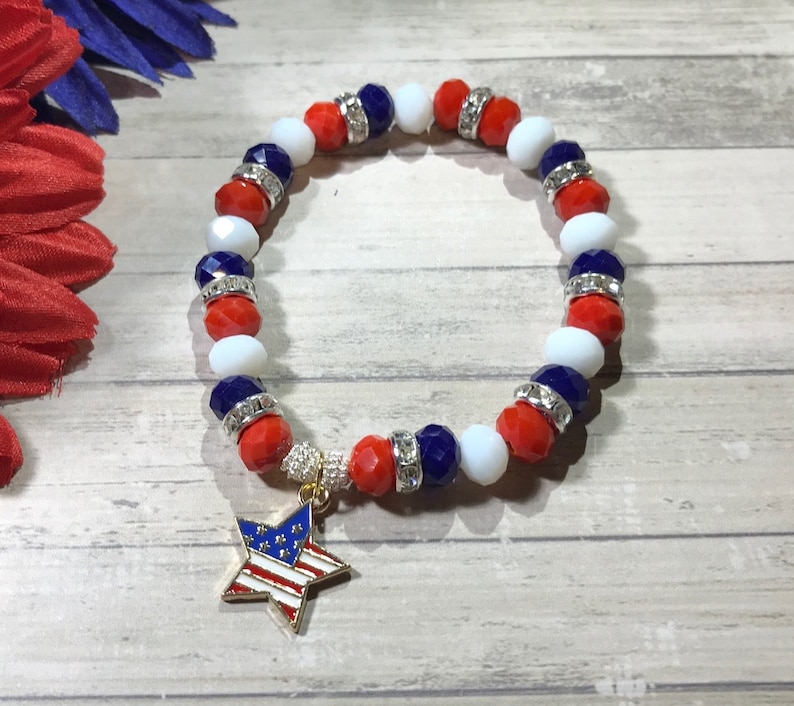 Pu&ograve; includere: Un braccialetto patriottico con perline rosse, bianche e blu, accentuato da distanziatori argentati. Un ciondolo a forma di stella dorata con un disegno della bandiera americana pende dal braccialetto. Il braccialetto &egrave; progettato per essere indossato al polso.