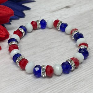 Puede incluir: Pulsera de cuentas rojas, blancas y azules, con separadores plateados. Las cuentas son facetadas. La pulsera el&aacute;stica parece hecha a mano, con tem&aacute;tica patri&oacute;tica.