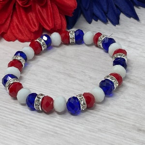 Puede incluir: Una pulsera de cuentas rojas, blancas y azules facetadas, intercaladas con espaciadores plateados incrustados con pedrer&iacute;a transparente. Un accesorio patri&oacute;tico, ideal para a&ntilde;adir un toque de color.