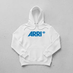 May include: White hoodie with a kangaroo pocket and drawstring hood. The front features the word "ARRI" in blue, with a smaller blue logo to the right. The hoodie is made of a soft material and is suitable for casual wear.