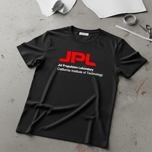 May include: Black crew neck t-shirt featuring the red letters "JPL" and the text "Jet Propulsion Laboratory California Institute of Technology". The shirt is made of a soft material.