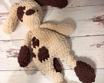Peut inclure: Un jouet en peluche crocheté à la main en forme de chien, fabriqué à partir de fil épais de couleur crème avec des taches marron foncé sur les oreilles, le visage, le torse et les pattes. L'animal en peluche présente de longues oreilles tombantes.