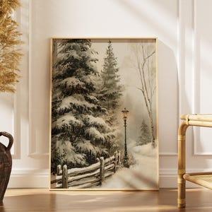May include: A vertical rectangular wall art print featuring a snowy winter landscape with tall evergreen trees covered in snow, a wooden fence, and a single glowing black street lamp illuminating a path through the forest in muted neutral tones.