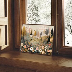以下が含まれることがあります： 小さな家が丘の上にあり、木や花に囲まれた風景を描いた、額入りのアートプリント。 暖色系の柔らかな色使いで、穏やかで魅力的なシーンを作り出しています。