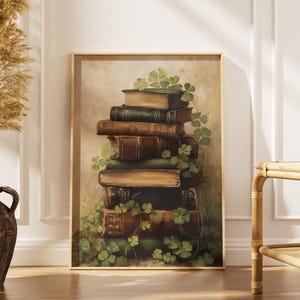 Puede incluir: Una impresión artística enmarcada que presenta una pila de libros antiguos con cubiertas de cuero. Los libros están adornados con tréboles verdes, creando una estética vintage. La obra de arte se exhibe en una habitación con un jarrón de plantas secas.