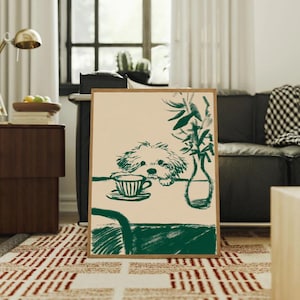 May include: A framed art print featuring a green and beige illustration. The artwork depicts a dog looking at a teacup on a table, with a vase of greenery. The print is in a wooden frame and is displayed in a living room setting.