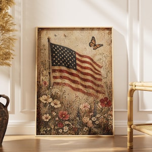 May include: A framed print featuring a vintage American flag waving in a field of wildflowers. The flag has red and white stripes and a blue field with white stars. A butterfly is flying near the flag. The print is in a wooden frame.