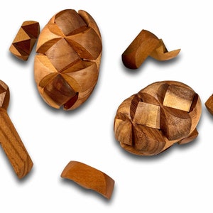 May include: A wooden puzzle with multiple pieces that fit together to form a sphere. The puzzle is made of light brown wood and has a natural finish.
