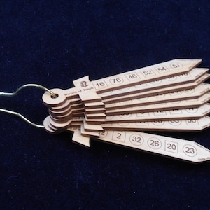 May include: A wooden sword of truth with a brass ring. The sword has a series of numbered wooden blades that can be rotated to reveal different numbers. The numbers on the blades are 2, 16, 20, 23, 26, 32, 46, 52, 54, 57, 60, 76, 80, 90, 100, 110, 120, 130, 140, 150, 160, 170, 180, 190, 200, 210, 220, 230, 240, 250, 260, 270, 280, 290, 300, 310, 320, 330, 340, 350, 360, 370, 380, 390, 400, 410, 420, 430, 440, 450, 460, 470, 480, 490, 500, 510, 520, 530, 540, 550, 560, 570, 580, 590, 600, 610, 620, 630, 640, 650, 660, 670, 680, 690, 700, 710, 720, 730, 740, 750, 760, 770, 780, 790, 800, 810, 820, 830, 840, 850, 860, 870, 880, 890, 900, 910, 920, 930, 940, 950, 960, 970, 980, 990, 1000.