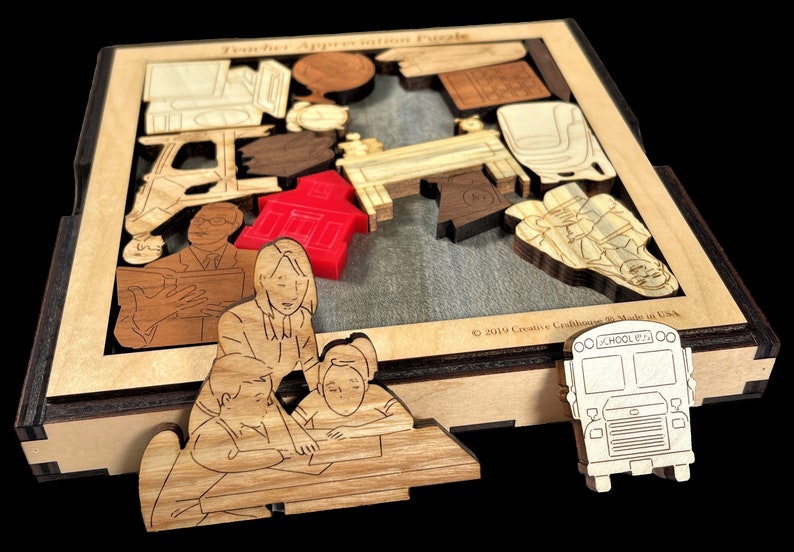 May include: Wooden teacher appreciation puzzle with a red schoolhouse, a school bus, and a teacher with students. The puzzle pieces are laser cut and fit together to create a complete picture.