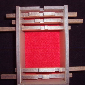 May include: A wooden box with a red felt lining and a series of wooden slats that can be moved around. The box is closed and the slats are in a random configuration.