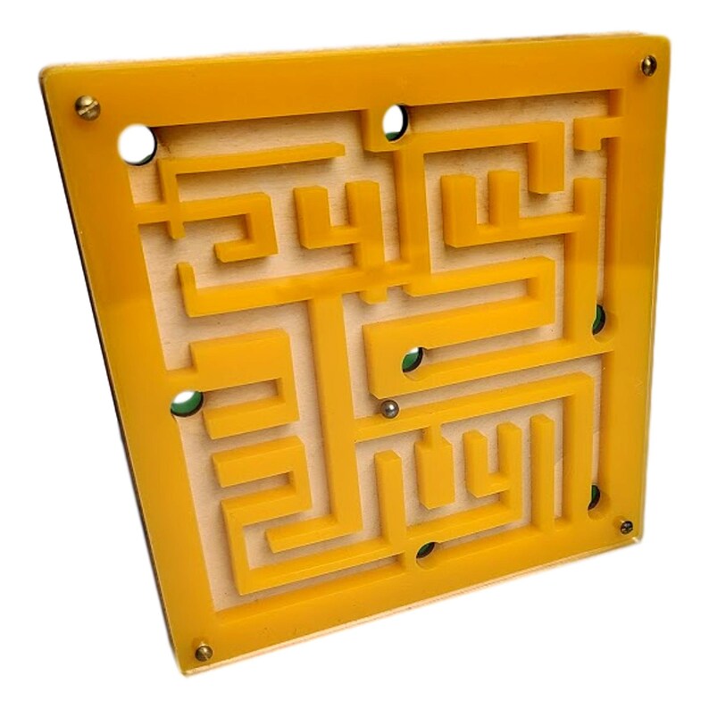 May include: A yellow maze game with a wooden base and a clear acrylic top. The maze features a complex pathway for a small metal ball to navigate. The game is square, with brass screws at each corner. The maze is a classic puzzle.