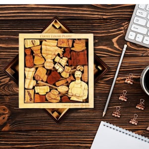 May include: A wooden coffee lovers puzzle with a barista in the center surrounded by coffee-themed pieces. The puzzle is in a wooden frame and has the text "Coffee Lovers Puzzle" at the top.
