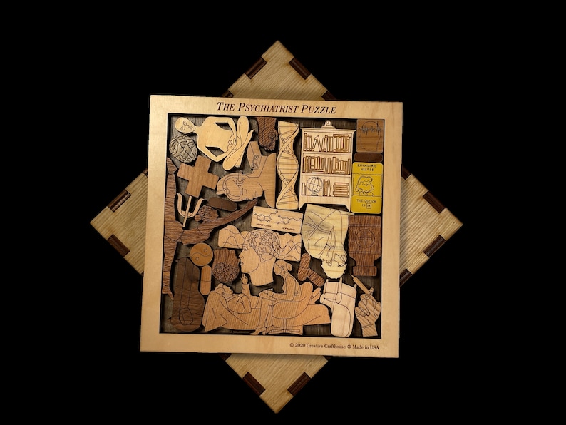 May include: A wooden puzzle with the title "The Psychiatrist Puzzle" and a variety of images including a brain, a cross, a book, a DNA strand, and a person meditating. The puzzle is made by Creative Craftshouse and is made in the USA.