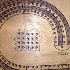 May include: A wooden game board with a circular track and a grid of holes. The track is marked with numbers from 1 to 120 and the grid is labeled with letters A through E and numbers 1 through 4. The board also has the word "FINISH" printed on it.