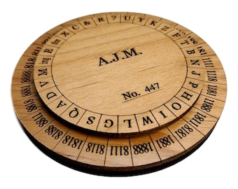 May include: A wooden circular puzzle with two rotating discs. The top disc has the letters of the alphabet and the bottom disc has numbers. The puzzle is labeled "A.J.M." and "No. 447".
