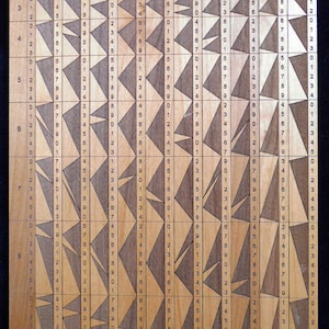 Può includere: Un tabellone di legno con un motivo a griglia e i numeri da 1 a 9 stampati su ogni riga e colonna. Il tabellone è diviso in quadrati, ognuno dei quali contiene un triangolo con un numero stampato al suo interno. I triangoli sono disposti in diagonale, creando un puzzle visivo.