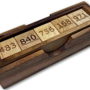 May include: Wooden box with a sliding lid containing five wooden blocks with numbers 483, 840, 756, 168, and 971 engraved on them.