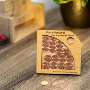 May include: Wooden game called Penny Packer 16. The game has a cutout in the shape of a quadrant and the instructions say to place 16 pennies inside the quadrant. The game is made of wood and has a natural wood finish. The game is made in the USA.