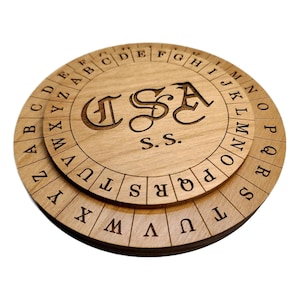 May include: A wooden cipher disk with two rotating layers. The top layer features the alphabet, while the bottom layer features a shifted alphabet. The disk is engraved with the letters "CSA" and "S.S."