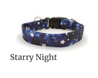 May include: A blue and black dog collar with a starry night print and white stars. The collar has a black plastic buckle and a silver D-ring. "Starry Night" is written below the collar.