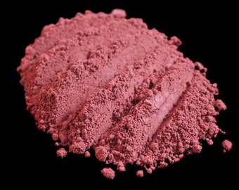 May include: A close-up of a pile of loose, red-brown powder. The powder is arranged in a series of ridges, creating a textured surface.
