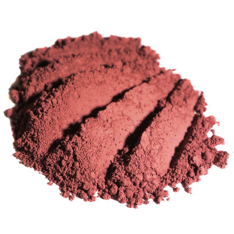 May include: A close-up of a pile of loose, red-brown powder. The powder is finely ground and has a smooth, even texture.