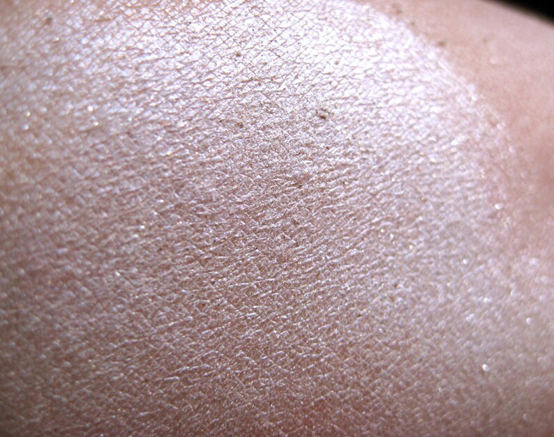Pu&ograve; includere: Primo piano di un ombretto perlato e scintillante con una texture liscia e uniforme.