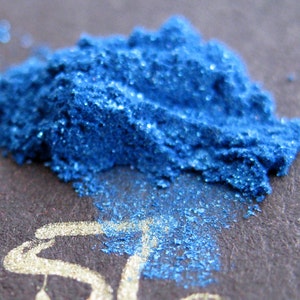 Puede incluir: Primer plano de un montón de pigmento de purpurina azul. La purpurina es muy fina y tiene un brillo metálico.