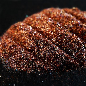 Könnte beinhalten: Nahaufnahme eines Haufens schimmernder kupferfarbener Glitter mit einer strukturierten, gewellten Oberfläche.