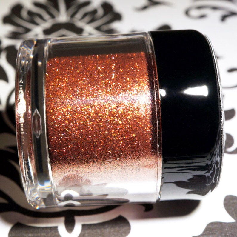 May include: A clear jar with a black lid filled with copper glitter.