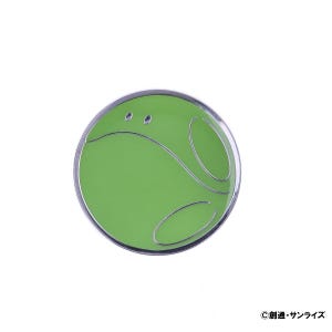 May include: A round, green pin with a silver border and a stylized design. The pin features a curved line and two small circles, creating a unique shape. The pin is set against a white background.