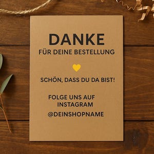 Könnte beinhalten: Eine braune Karte mit dem deutschen Text "DANKE" und "FÜR DEINE BESTELLUNG" in Schwarz. Darunter steht "SCHÖN, DASS DU DA BIST!" und "FOLGE UNS AUF INSTAGRAM @DEINSHOPNAME". In der Mitte befindet sich ein gelbes Herz. Die Karte liegt auf einer Holzoberfläche.