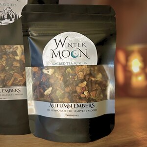 May include: A black pouch of "Autumn Embers" herbal tea from Winter Moon, with a clear window showing the tea blend. The label reads "In Honor of the Harvest Moon" and "Caffeine Free."