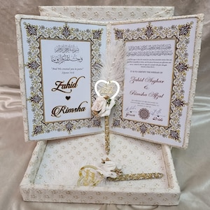 May include: A wedding gift set with two open books, featuring gold and white ornate frames. The books display text in Arabic and English, with the names Zahid and Rimsha. A heart-shaped ornament and a pen are included.