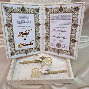 May include: A white wedding invitation set with gold detailing, featuring the names "Fahid" and "Rimsha." The set includes a decorative box, two pens, and a certificate with ornate borders and Arabic script.