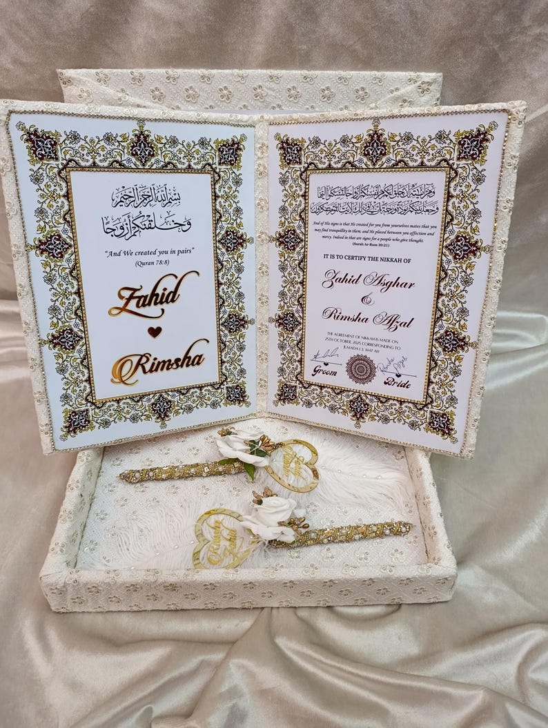 May include: A white wedding invitation set with gold detailing, featuring the names "Fahid" and "Rimsha." The set includes a decorative box, two pens, and a certificate with ornate borders and Arabic script.